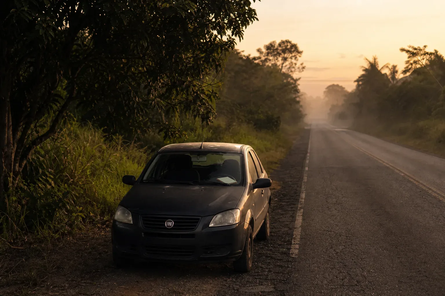Carro parado em estrada vazia ao amanhecer